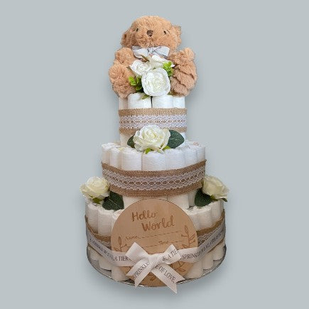 3 tier uncovered nappy cake, tied with Hessian & Lace Ribbon, topped with a brown teddy bear and a Hello World plaque tied to the bottom tier