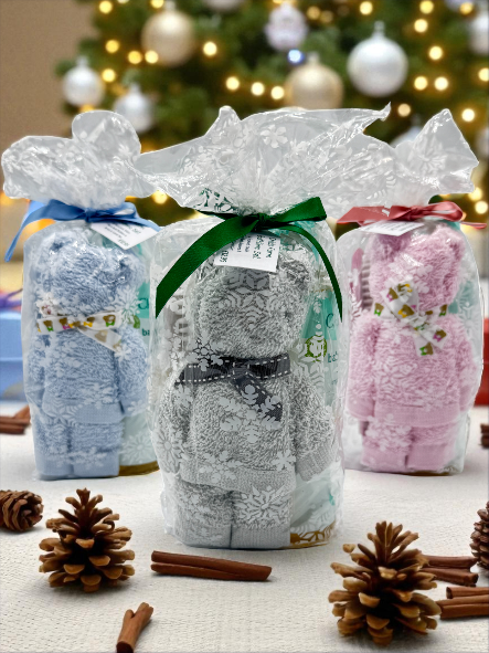 Three wrapped gifts with decorative ribbons on a table with Christmas decorations in the background.