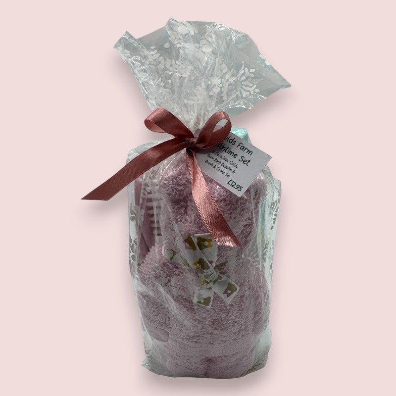 The Love & Tiers "Childs Farm Bath Set", a Gift set wrapped in clear and seasonal print cellophane with a pink ribbon on a light pink background