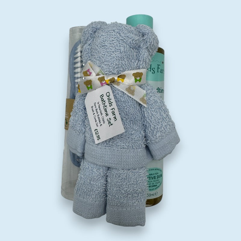 Child's bath time set with blue face cloth, brush, and bottles on a light blue background