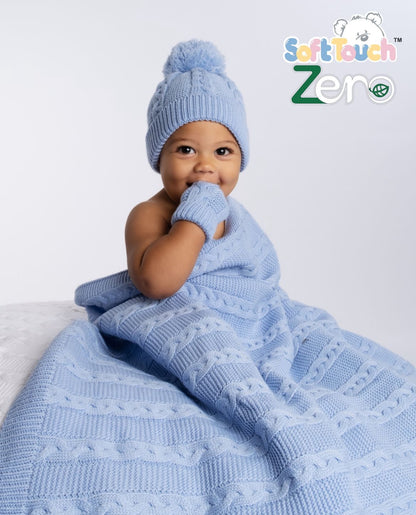 Baby wearing the blue cable knit baby wrap, along with the matching bobble hat and mittens, ideal for keeping babies warm and cosy