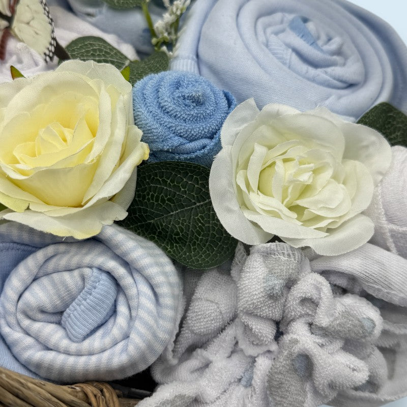 Rolled up baby blankets in blue and gray with flowers on a textured surface