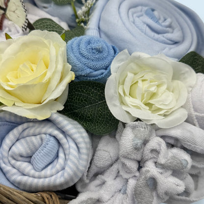 Rolled up baby blankets in blue and gray with flowers on a textured surface