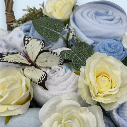 Bouquet of flowers and rolled up baby clothes with a butterfly on a light blue background