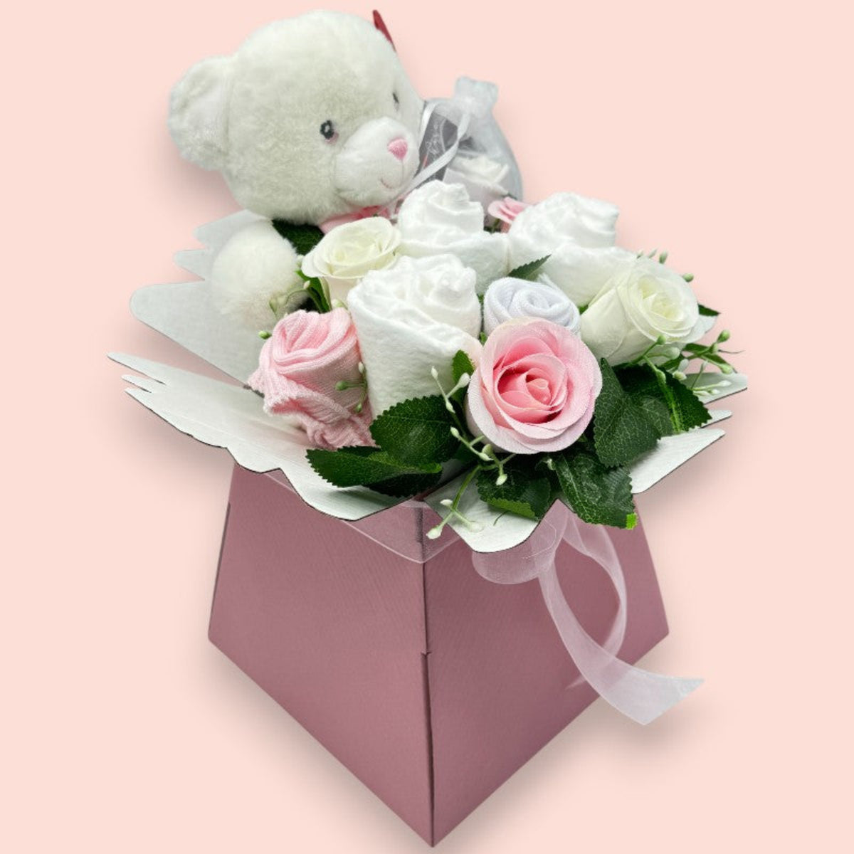 Side view of pink Baby Blossom gift box with teddy bear, baby essentials and floral arrangement