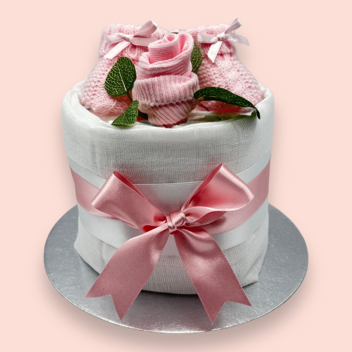 Baby girl nappy cake with pink knitted booties, sock rose, muslin and satin ribbon