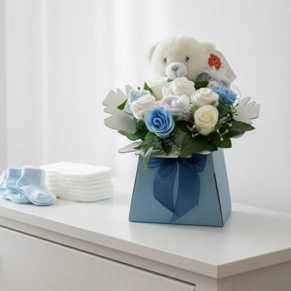 Blue Baby Blossom gift box styled in a nursery with teddy bear, baby essentials and blue and white roses