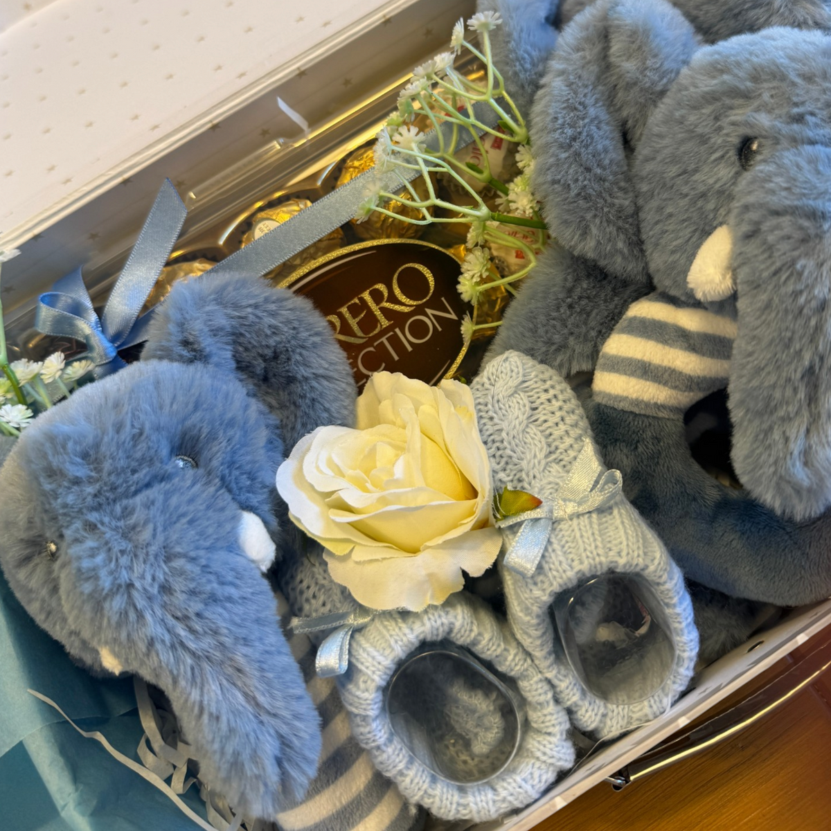 Close-up of chocolates and decorative foliage in a blue baby gift suitcase