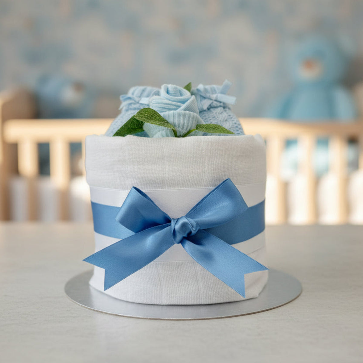 Blue nappy cake with knitted booties styled in a soft nursery setting