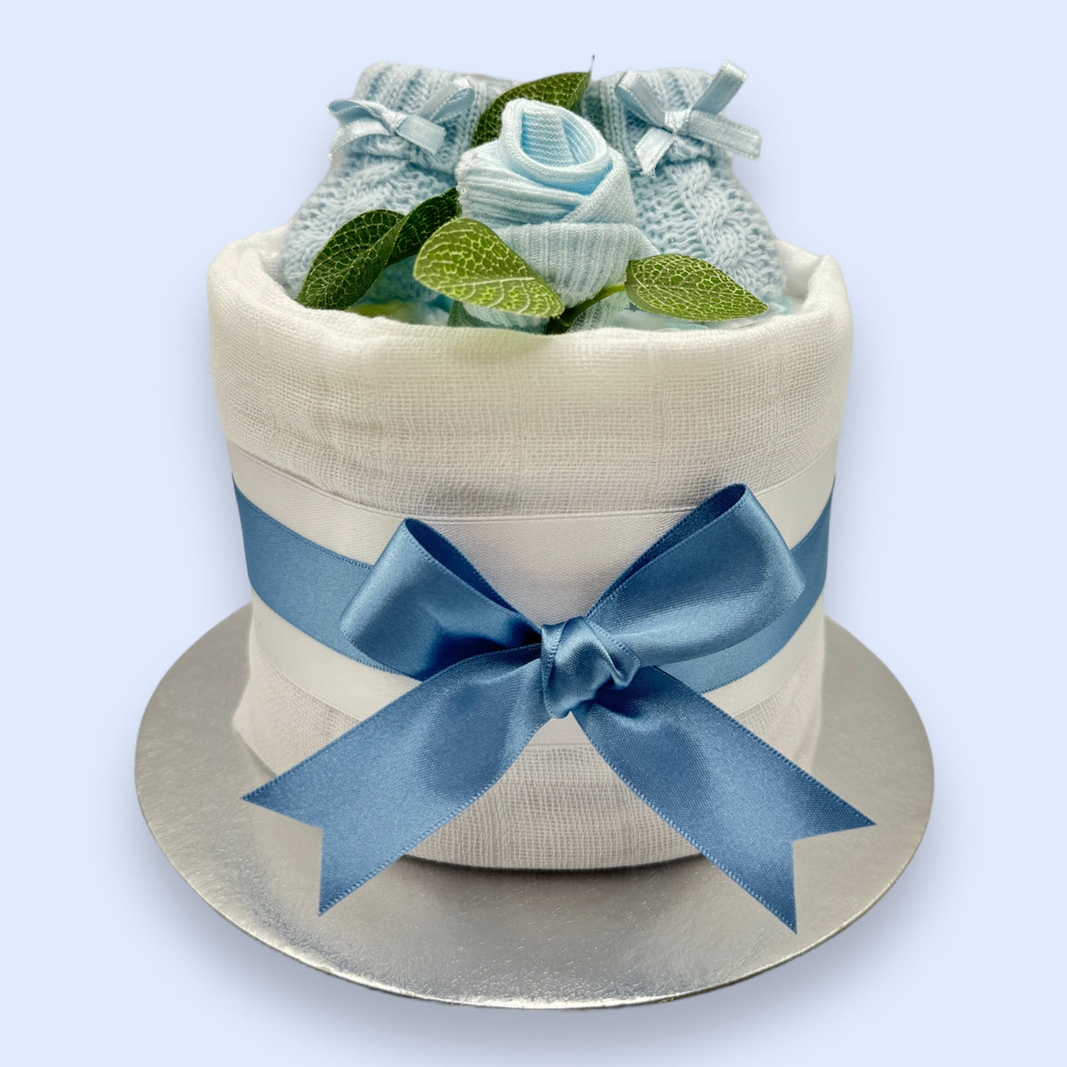 Blue baby nappy cake showing Pampers nappies, knitted booties and baby sock rose