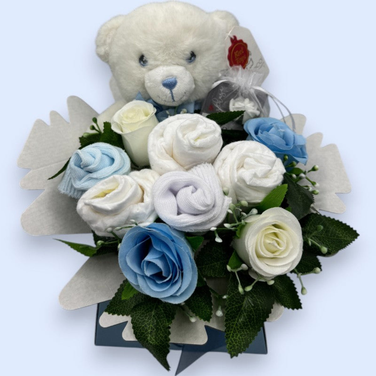 Top view of blue newborn gift box with nappies, baby socks, Keeleco teddy and blue and white roses