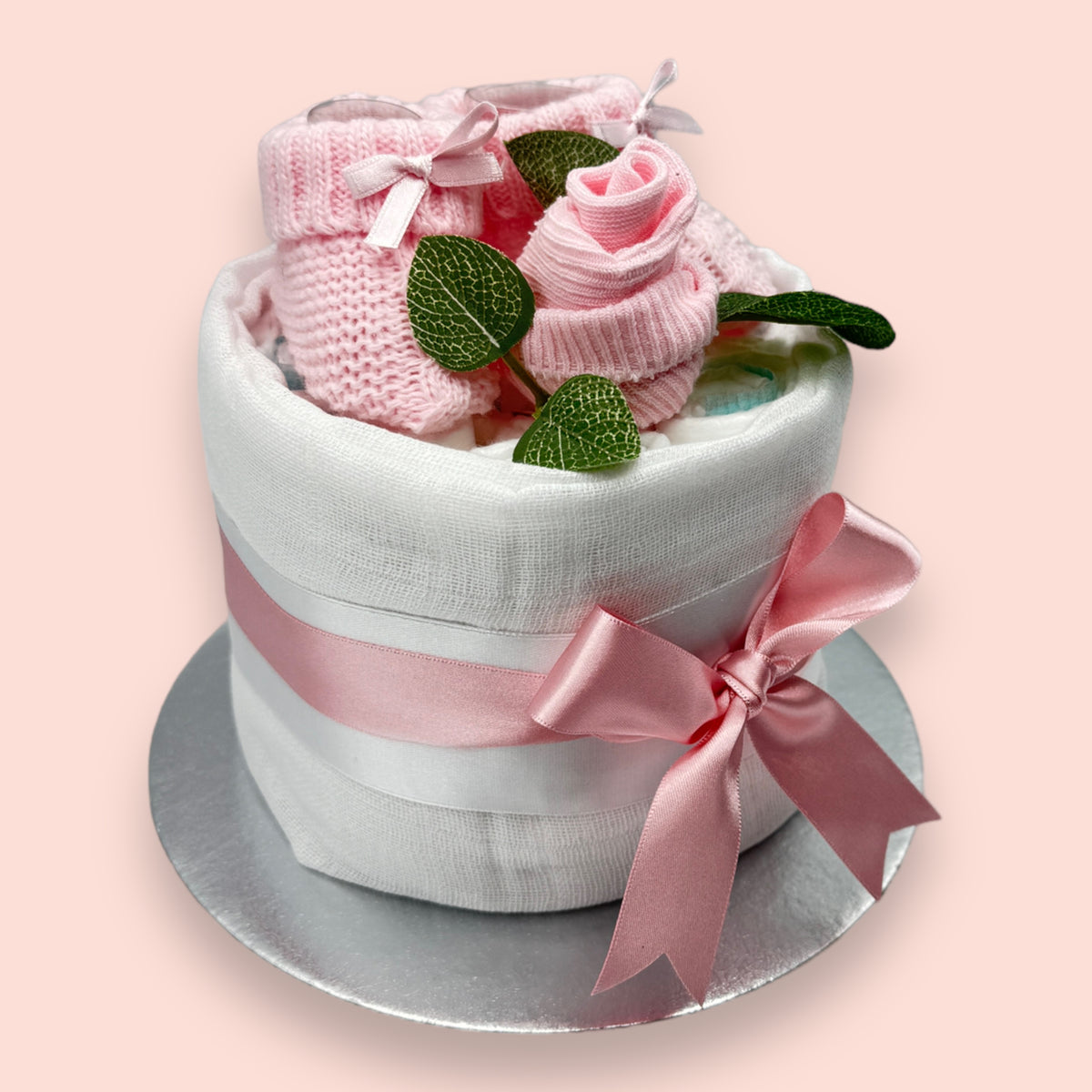 Handmade pink nappy cake with white muslin, baby booties and satin bow