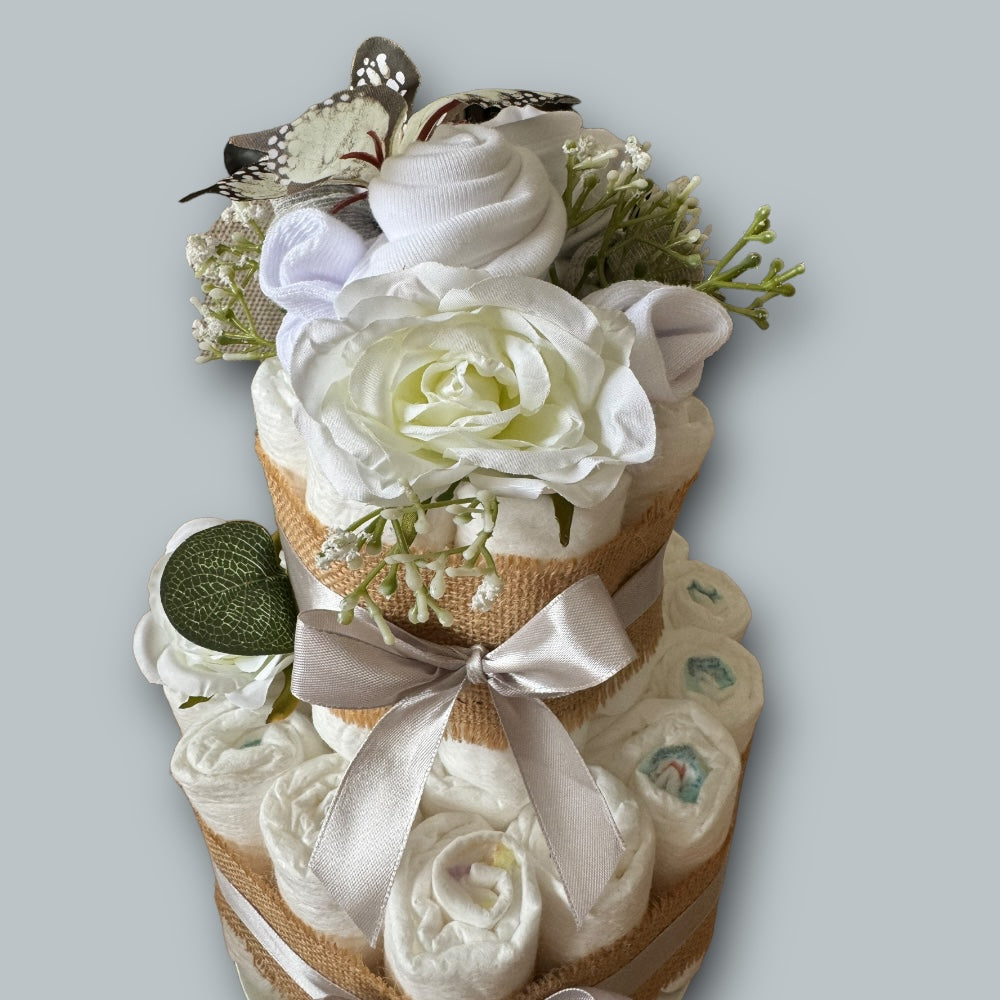 Baby bodysuit hat and socks arranged as floral topper on nappy cake