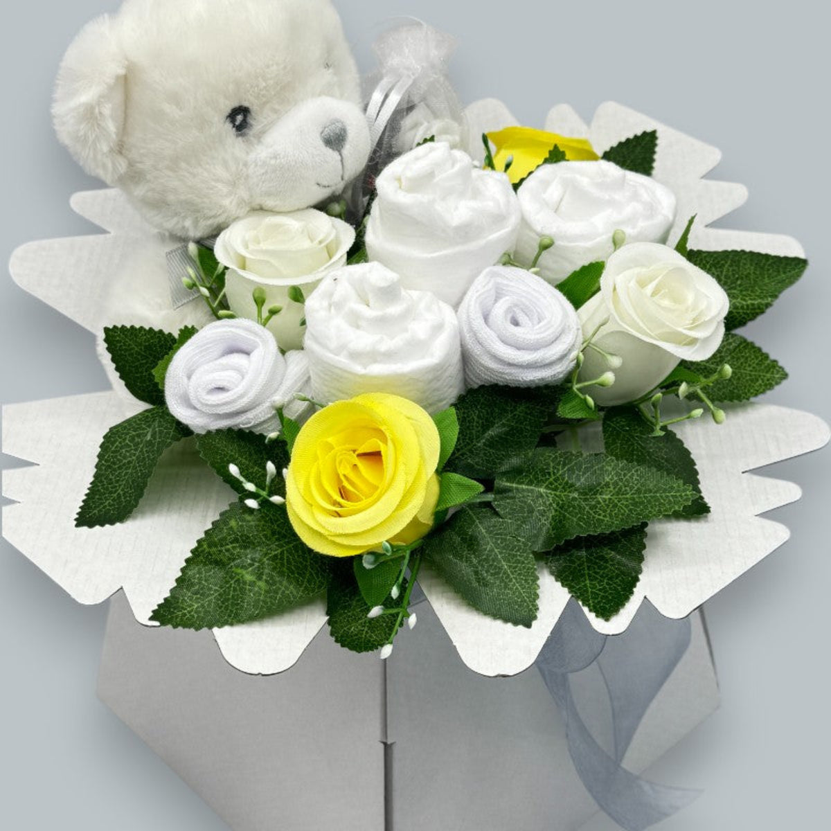Side view of neutral Baby Blossom gift box with teddy bear, baby essentials and floral arrangement