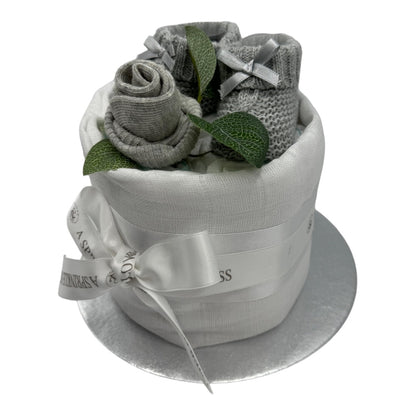 Side view of mini neutral nappy cake with grey knitted baby booties