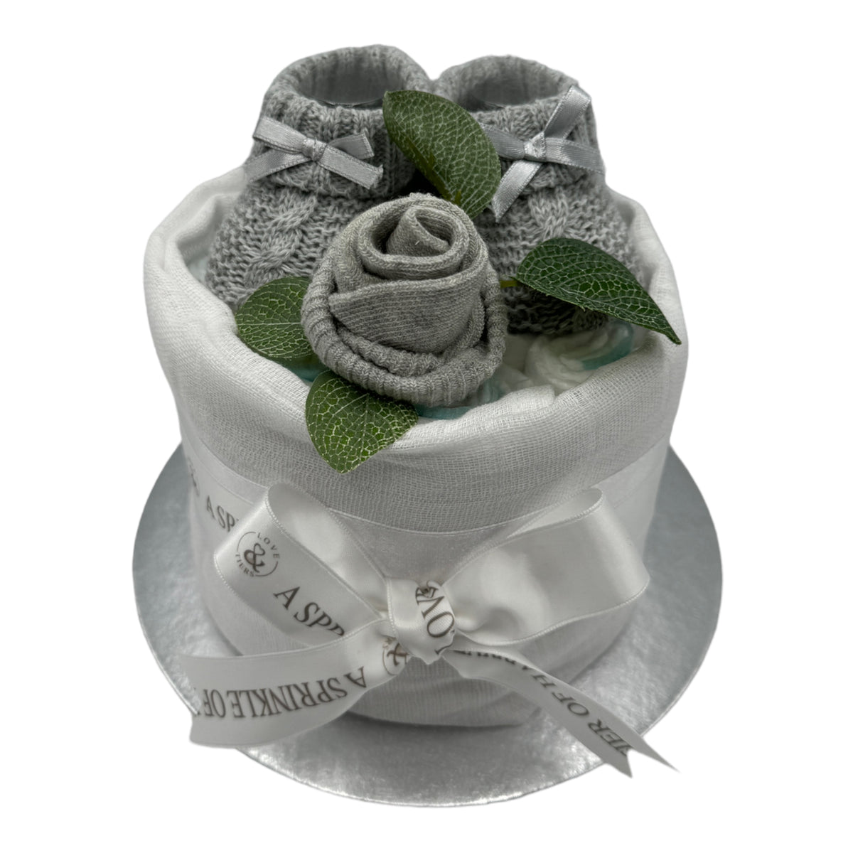 Neutral baby nappy cake showing Pampers nappies, grey knitted booties and baby sock rose
