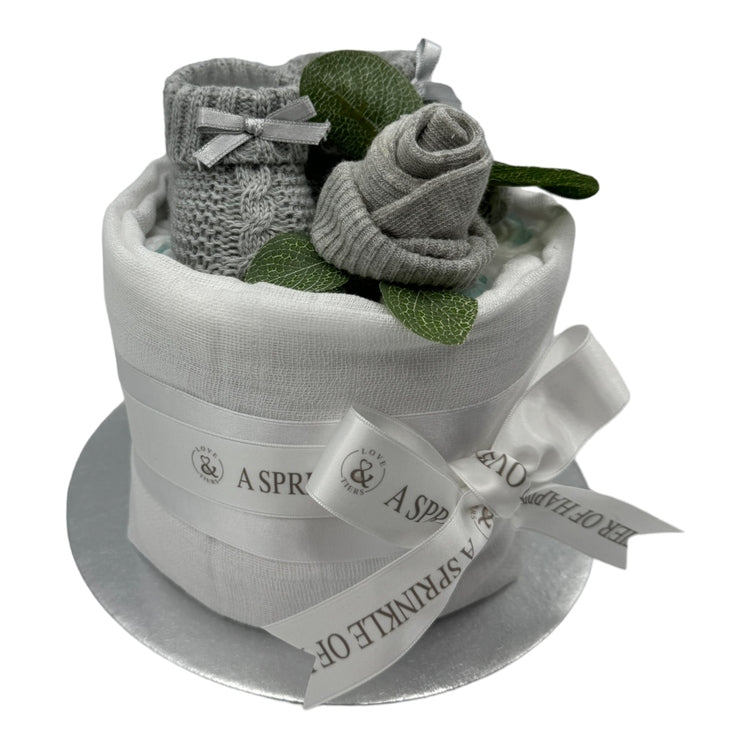 Handmade neutral baby nappy cake with grey knitted booties and white ribbon. with a white background