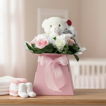 Pink Baby Blossom newborn baby girl gift box styled in a nursery with teddy bear, nappies, baby socks and roses