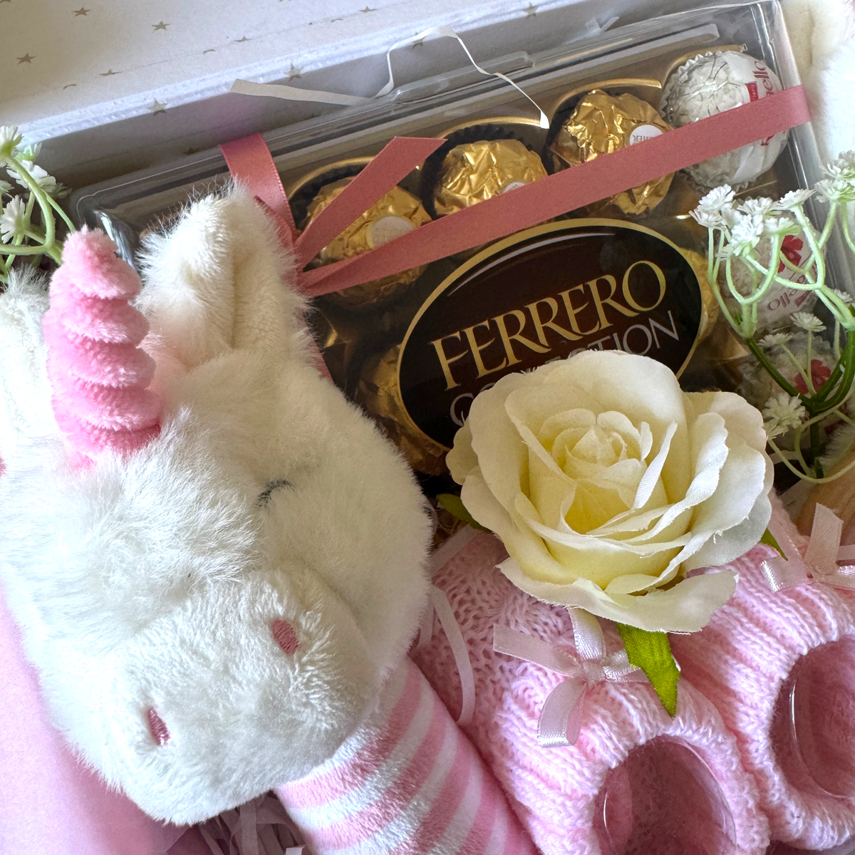Close-up of chocolates and decorative foliage in a pink baby gift suitcase