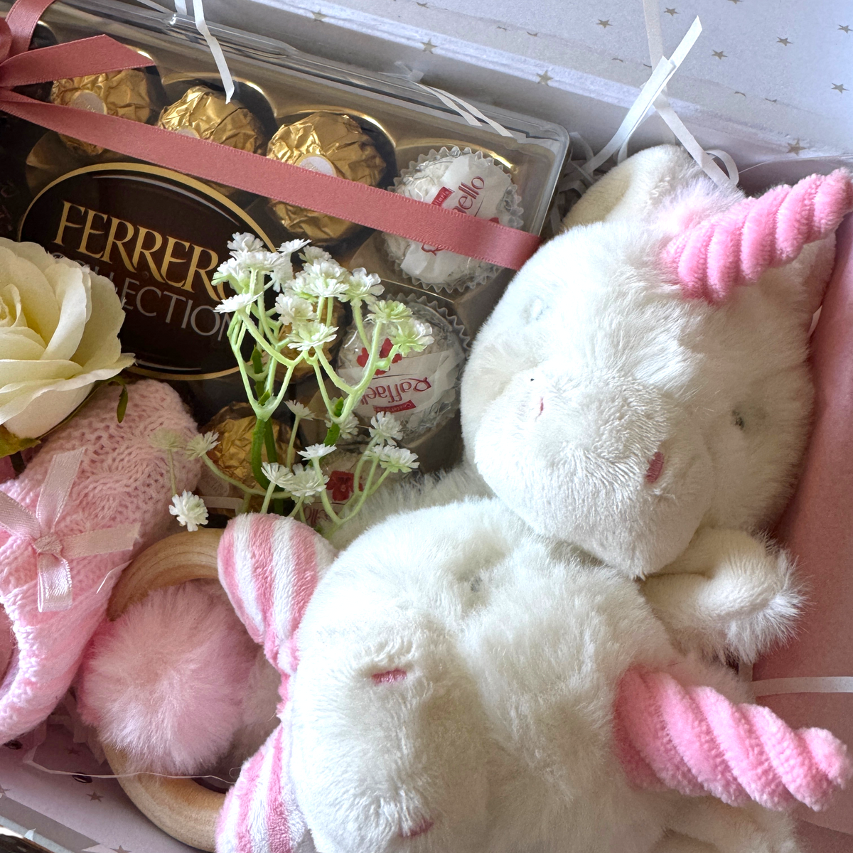 Close-up of soft toys and pink baby booties in a baby gift suitcase