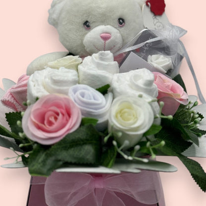 Close-up of pink Baby Blossom baby girl gift with teddy bear, roses and practical baby essentials